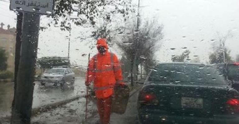 عامل وطن اثناء قيامه بعمله تحت المطر في العاصمة عمان.. تصوير الزميل داود كتاب