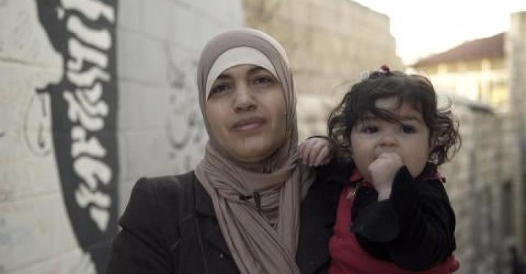 امرأة أردنية متزوجة من رجل أجنبي، تحمل طفلتها، وهي واحدة من أبنائها الأربعة غير الحاصلين على الجنسية الأردنية. الصورة © أماندا بايلي لـ هيومن رايتس ووتش