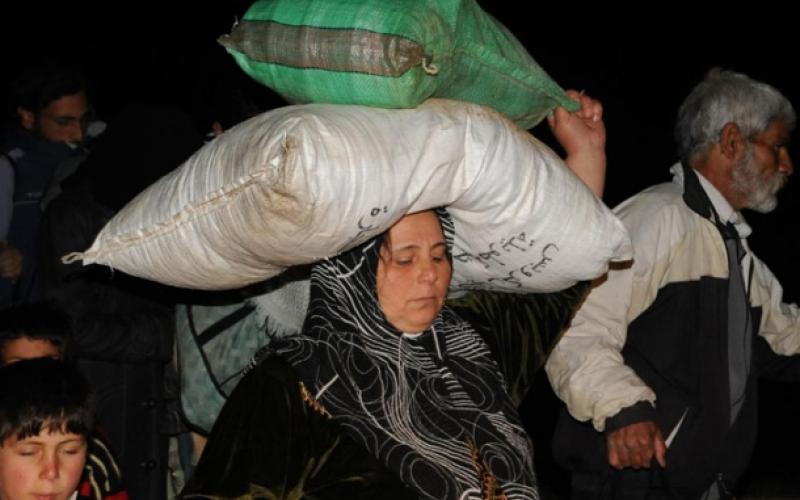 لاجئة تحمل بعض حاجياتها خلال النزوح للاردن