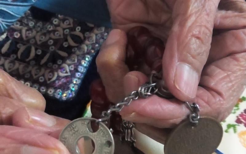 عملة فلسطينة بيد لاجئة مسنة بالوحدات