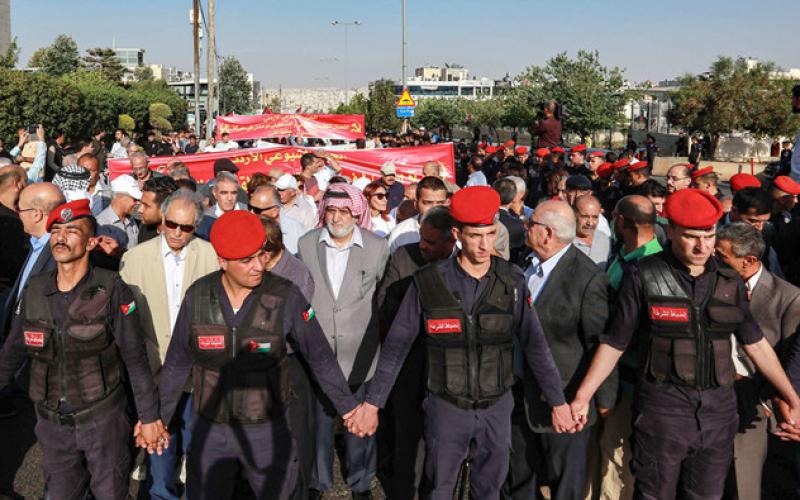 Jordanian security forces create a security perimeter around protesters participating in the "March of Anger" demonstration leading to the US embassy headquarters in the Jordanian capital Amman on June 21, 2019, against the US President Donald Trump's "Deal of the Century" and the US-led Middle East economic conference in Bahrain. (AFP)